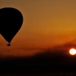 Globo aerostatico en silueta sobre un amanecer dorado en Luxor Egipto con el sol bajo en el horizonte junto al valle del Nilo