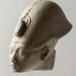 Cabeza de piedra caliza del faraon Akhenaton con su rostro alargado caracteristico, ojos almendrados, labios carnosos y menton fino, arte de Amarna