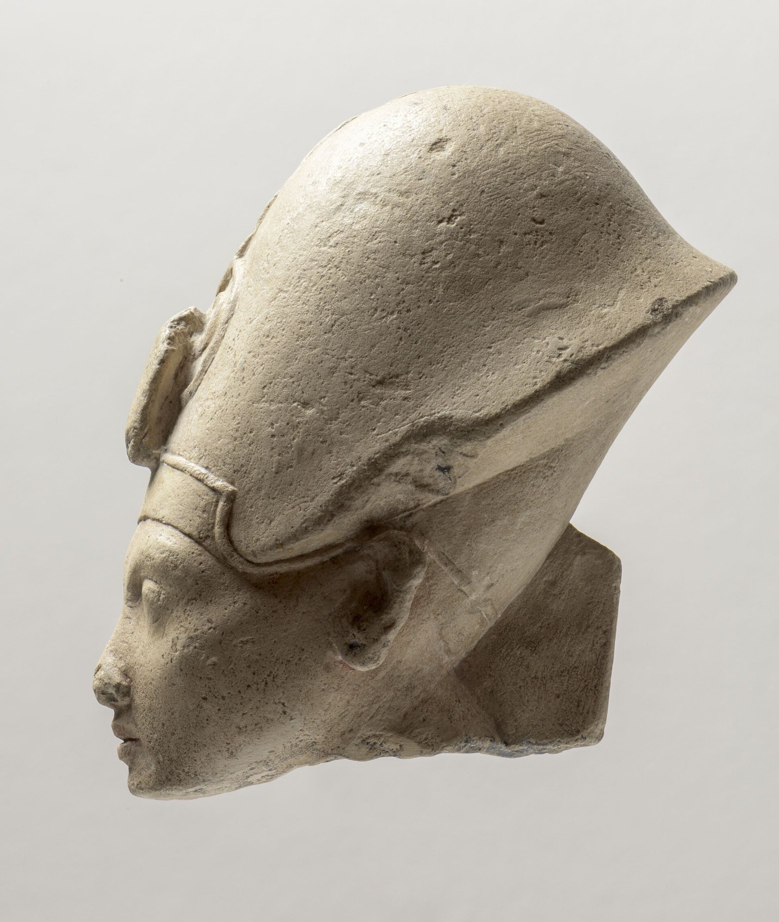 Cabeza de Akhenaton vista de perfil en piedra caliza palida con corona y el rostro alargado del arte de Amarna, imagen nitida