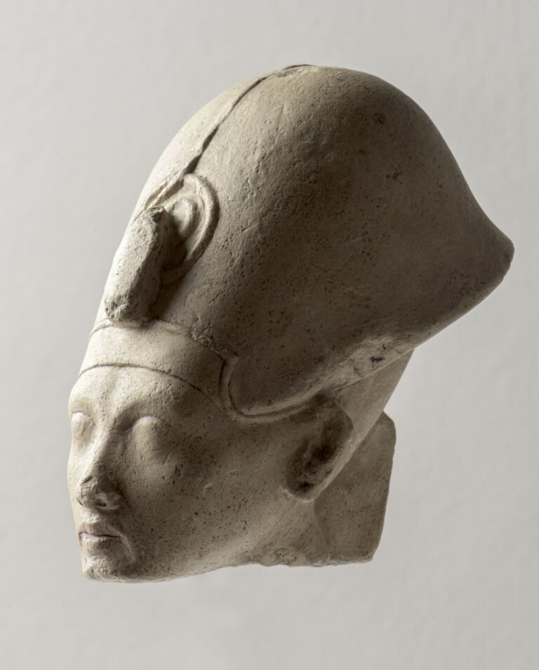Cabeza de piedra caliza del faraon Akhenaton con su rostro alargado caracteristico, ojos almendrados, labios carnosos y menton fino, arte de Amarna