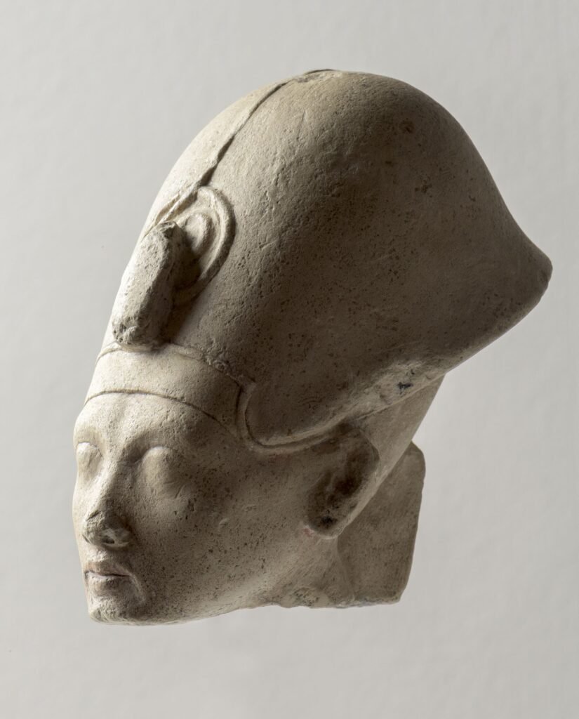 Cabeza de piedra caliza del faraon Akhenaton con su rostro alargado caracteristico, ojos almendrados, labios carnosos y menton fino, arte de Amarna