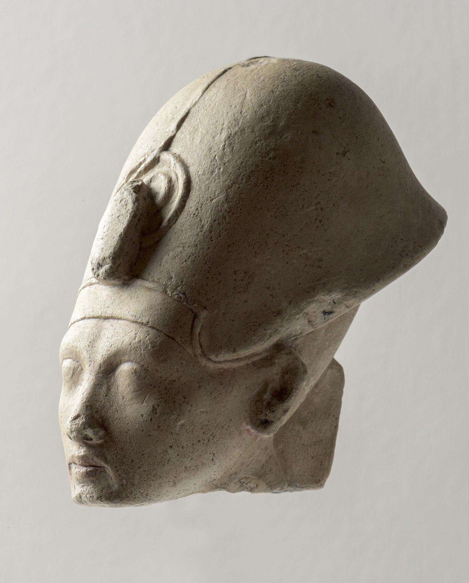 Cabeza de piedra caliza del faraon Akhenaton con su rostro alargado caracteristico, ojos almendrados, labios carnosos y menton fino, arte de Amarna