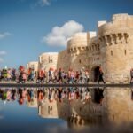 La Ciudadela de Qaitbay en Alejandria con su reflejo en el agua, muros de piedra dorada bajo un cielo azul y la corniche junto al Mediterraneo