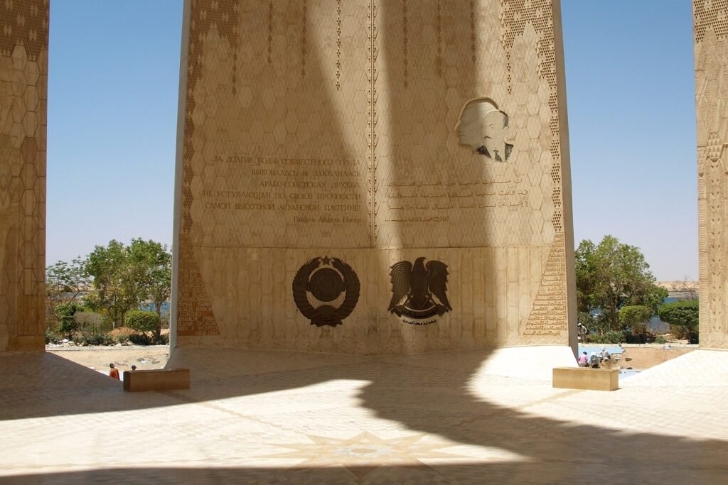 Monumento del loto de la Alta Presa de Asuan en Egipto, con emblemas grabados e inscripciones bajo el arco de piedra y vegetacion alrededor