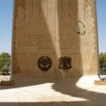 Monumento del loto de la Alta Presa de Asuan en Egipto, con emblemas grabados e inscripciones bajo el arco de piedra y vegetacion alrededor