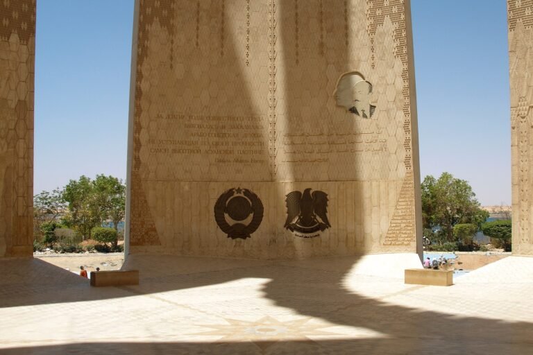 Monumento del loto de la Alta Presa de Asuan en Egipto, con emblemas grabados e inscripciones bajo el arco de piedra y vegetacion alrededor