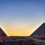 Las dos grandes piramides de Giza y la silueta de la Esfinge recortadas contra un cielo de atardecer naranja y azul en Egipto