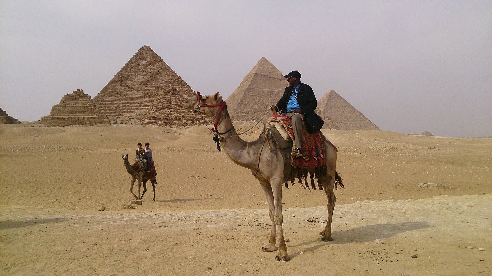 Hombre montado en un camello frente a las piramides de Guiza en Egipto para planificar un viaje a Egipto
