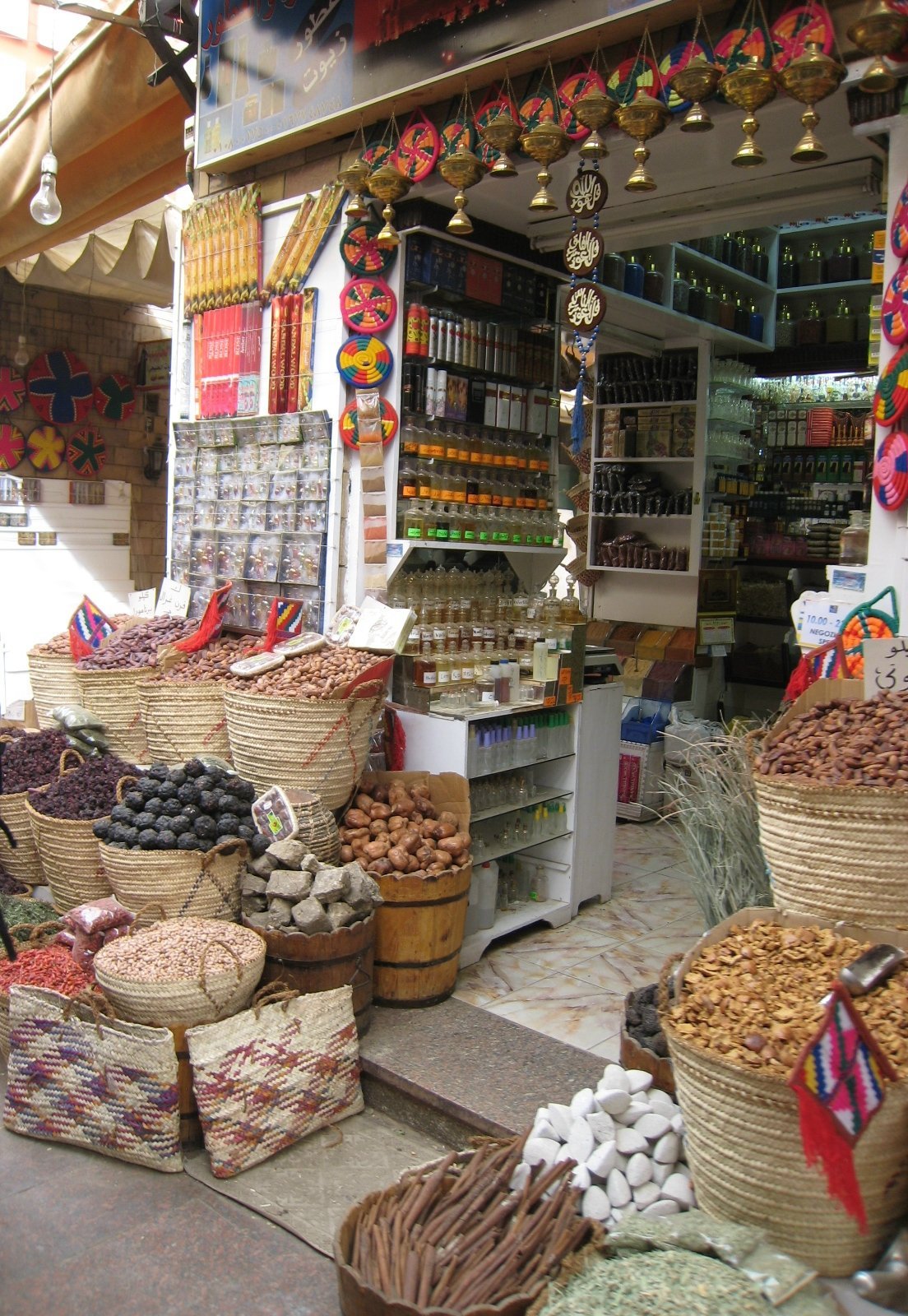 Puesto de especias en un zoco egipcio con cestas de mimbre llenas de frutos secos y artesanias colgantes de colores bajo la luz del dia