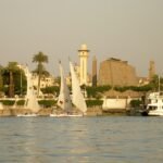 Crucero por el Nilo en diciembre junto a los templos de Luxor con felucas de vela blanca y luz dorada al atardecer