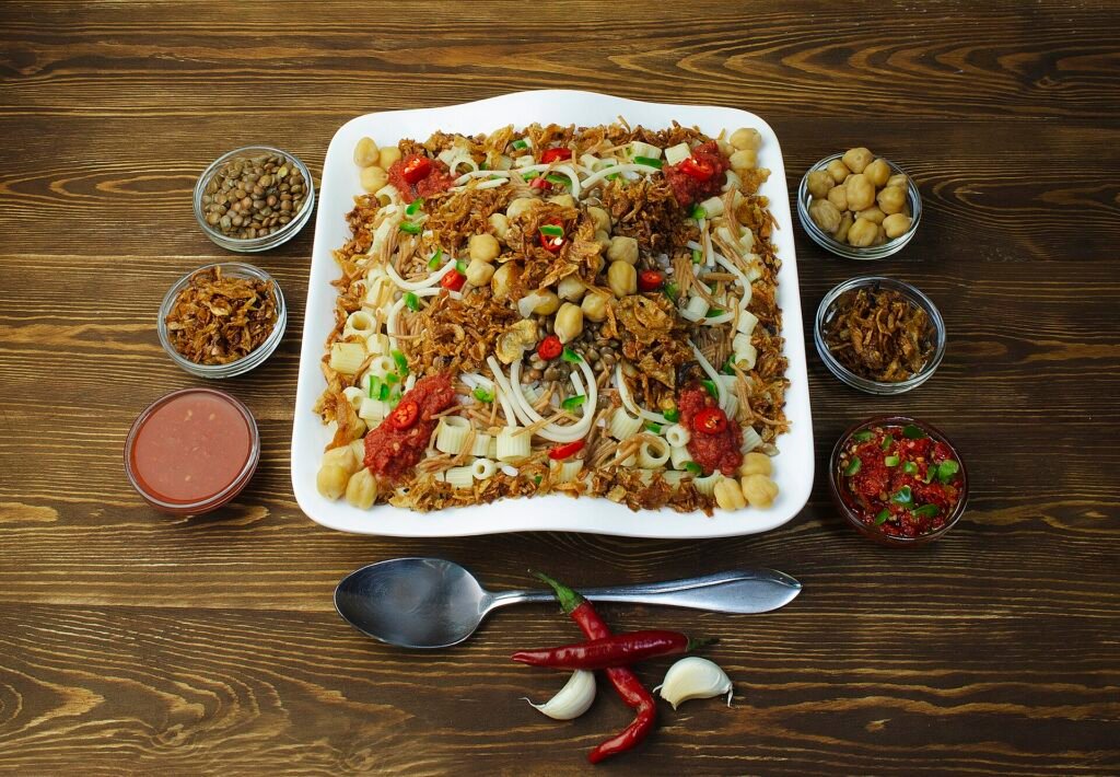 Plato de koshari egipcio con arroz lentejas garbanzos macarrones y cebolla frita servido en mesa de madera comida tradicional de Egipto