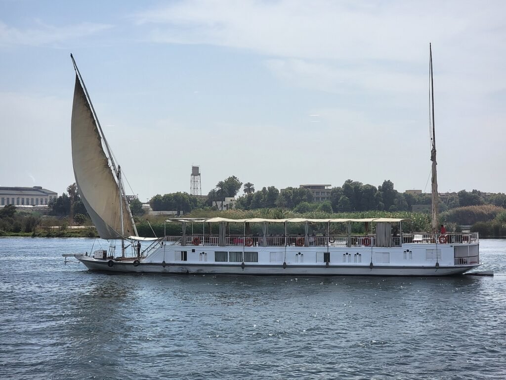 Dahabiya tradicional con gran vela latina blanca desplegada navegando por el Nilo en Egipto