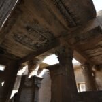 Sala hipostila de un templo ptolemaico bien conservado en Deir el-Medina, Luxor, Egipto, con techo pintado y capiteles tallados iluminados por el sol