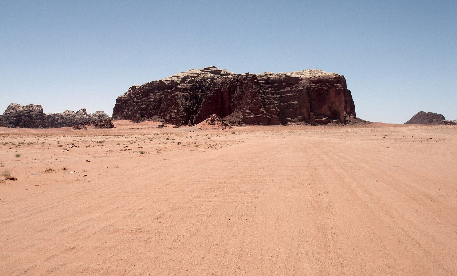 Desierto de Wadi Rum con gran formacion rocosa roja sobre arena dorada, Jordania