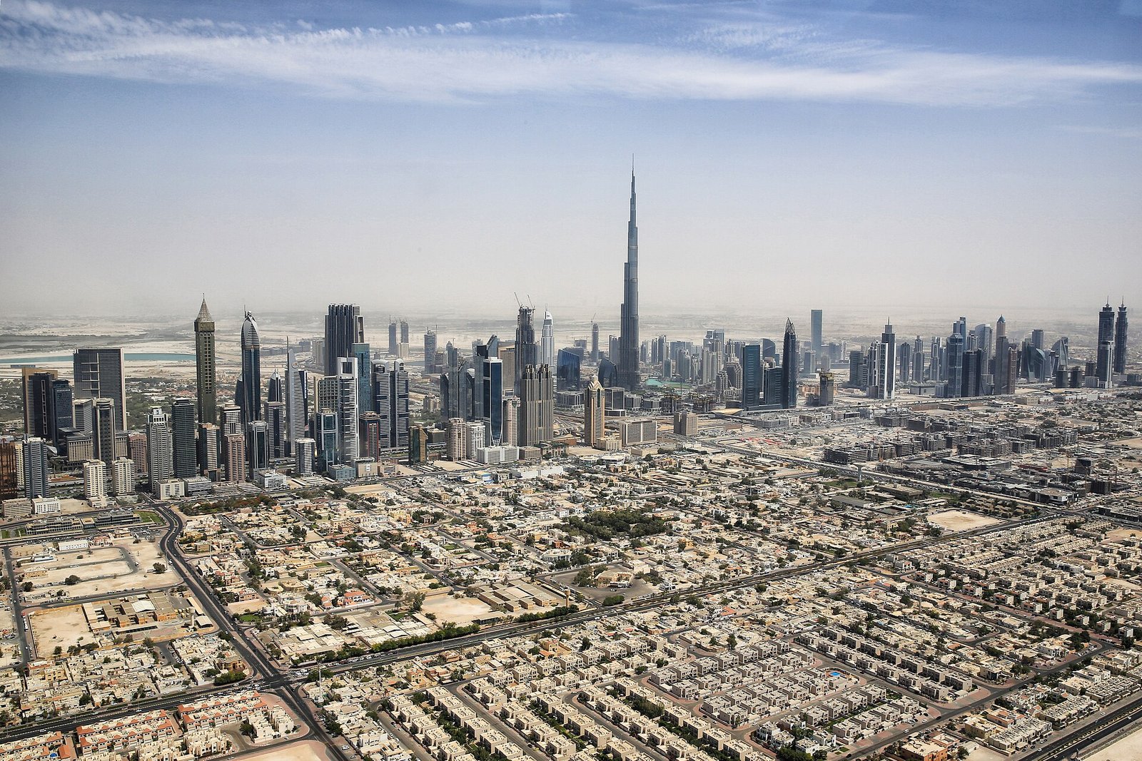 Vista aerea de Dubai con el Burj Khalifa dominando el horizonte de rascacielos modernos bajo un cielo azul, ciudad premium de Emiratos