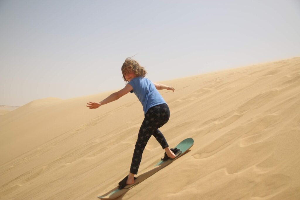 Aventura en el desierto de Egipto, una persona haciendo sandboard descendiendo una gran duna dorada bajo cielo despejado, escena energica y premium