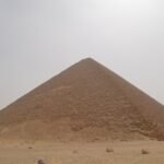 La Piramide Roja de Dahshur se eleva simetrica sobre el desierto abierto bajo un cielo despejado, una de las grandes piramides lisas del antiguo Egipto
