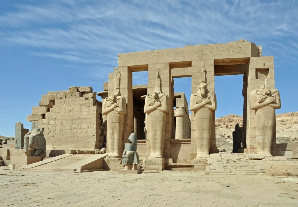 The second court of the Ramesseum at Luxor, four Osiride statues of Ramesses II standing along the terrace with the temple gateway behind
