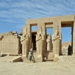 The second court of the Ramesseum at Luxor, four Osiride statues of Ramesses II standing along the terrace with the temple gateway behind