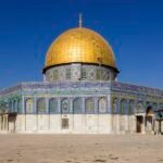 La Cupula de la Roca dorada en la Ciudad Vieja de Jerusalen, Tierra Santa, con su base octogonal de mosaicos azules bajo un cielo despejado