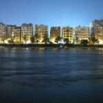 Horizonte de El Cairo al atardecer sobre el rio Nilo en Egipto, con edificios iluminados en luz dorada y el agua tranquila en primer plano