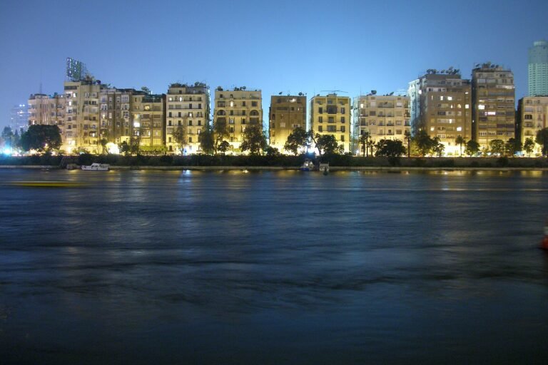 Horizonte de El Cairo al atardecer sobre el rio Nilo en Egipto, con edificios iluminados en luz dorada y el agua tranquila en primer plano