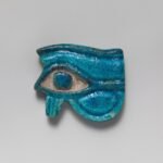 Amuleto wedjat egipcio en fayenza turquesa vidriada, con ceja, ojo y pupila bien definidos, simbolo protector del Ojo de Horus sobre fondo neutro