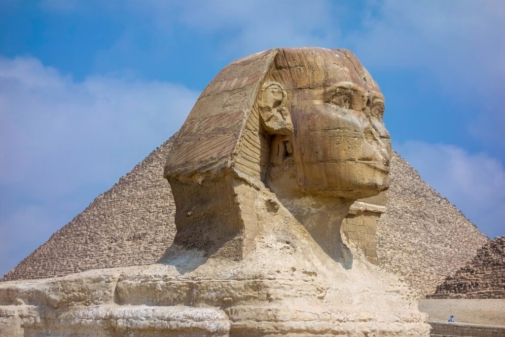 La Gran Esfinge de Giza con la Gran Piramide elevandose justo detras bajo un cielo azul, la imagen mas iconica de Egipto