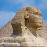 La Gran Esfinge de Giza con la Gran Piramide elevandose justo detras bajo un cielo azul, la imagen mas iconica de Egipto
