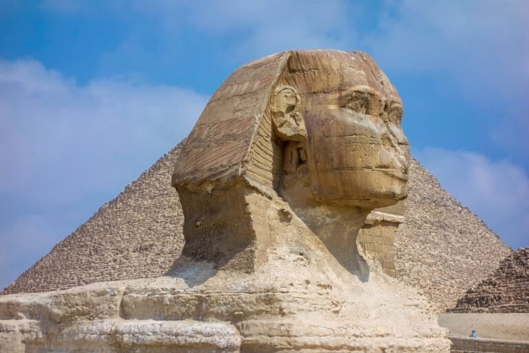 La Gran Esfinge de Giza con la Gran Piramide elevandose justo detras bajo un cielo azul, la imagen mas iconica de Egipto
