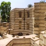 Las torres redondas de piedra romana de la Fortaleza de Babilonia en El Cairo Copto, Egipto, con bandas de ladrillo rojo, arcos ciegos y palmeras bajo cielo azul