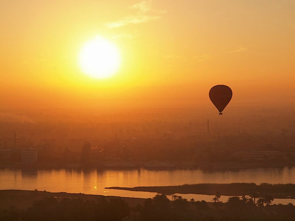 Globo aerostático sobrevolando Luxor y el río Nilo al amanecer dorado, Alto Egipto