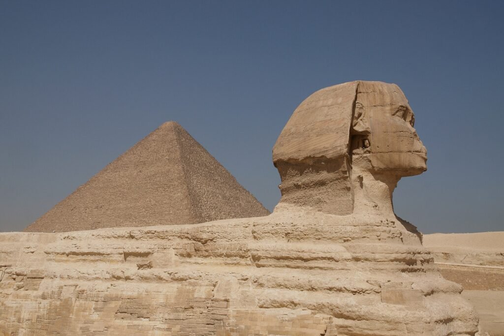 La Gran Esfinge de Giza de perfil con la piramide de Keops detras, Egipto, cielo azul