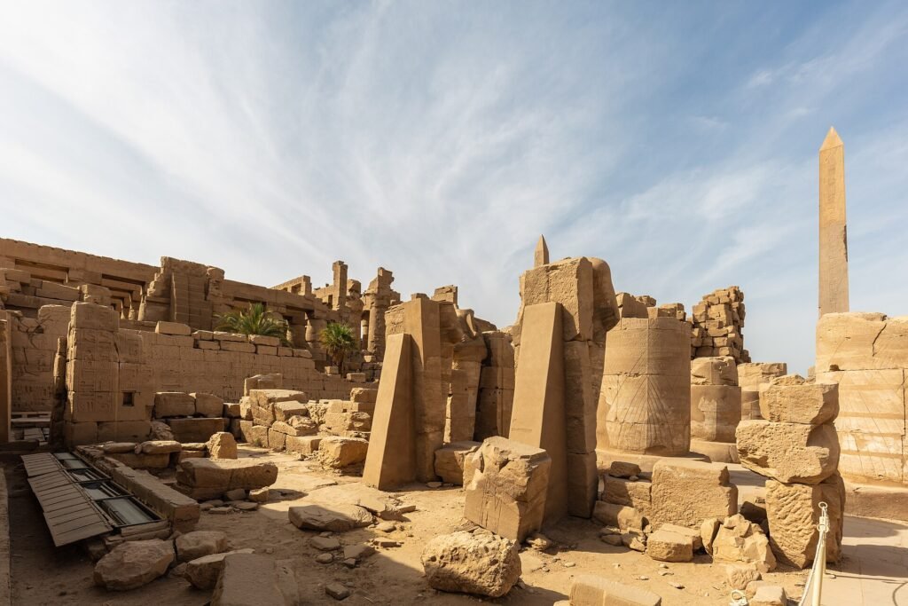 Templo de Karnak en Luxor Egipto con su obelisco columnas y muros de piedra arenisca iluminados bajo un cielo azul con nubes