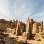 Templo de Karnak en Luxor Egipto con su obelisco columnas y muros de piedra arenisca iluminados bajo un cielo azul con nubes