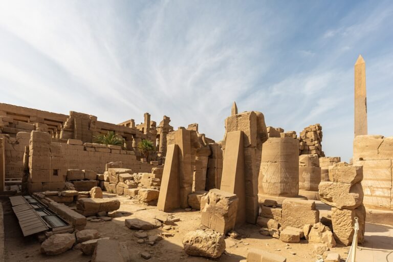 Templo de Karnak en Luxor Egipto con su obelisco columnas y muros de piedra arenisca iluminados bajo un cielo azul con nubes
