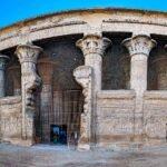 Templo de Esna dedicado al dios Khnum a orillas del Nilo en Egipto, con su sala hipostila de columnas talladas y capiteles vegetales bajo un cielo azul