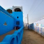 Callejon de un pueblo nubio en Egipto con casas pintadas de azul cobalto intenso, cupula y cenefa de triangulos de colores bajo cielo despejado, rincon muy fotogenico