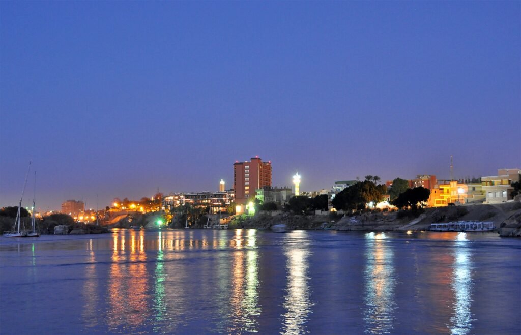 El Nilo en Asuan a la hora azul del anochecer con las luces de la ciudad reflejadas en el agua