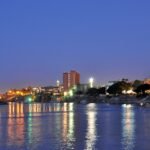 El Nilo en Asuan a la hora azul del anochecer con las luces de la ciudad reflejadas en el agua
