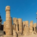 Columnas monumentales y estatuas colosales de Ramses en el patio del Templo de Luxor con jeroglificos bajo un cielo azul intenso en Egipto