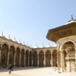 Patio de alabastro de la mezquita de Muhammad Ali en El Cairo, Egipto, con el pabellón dorado de la fuente y la arcada de cupulas blancas bajo cielo azul