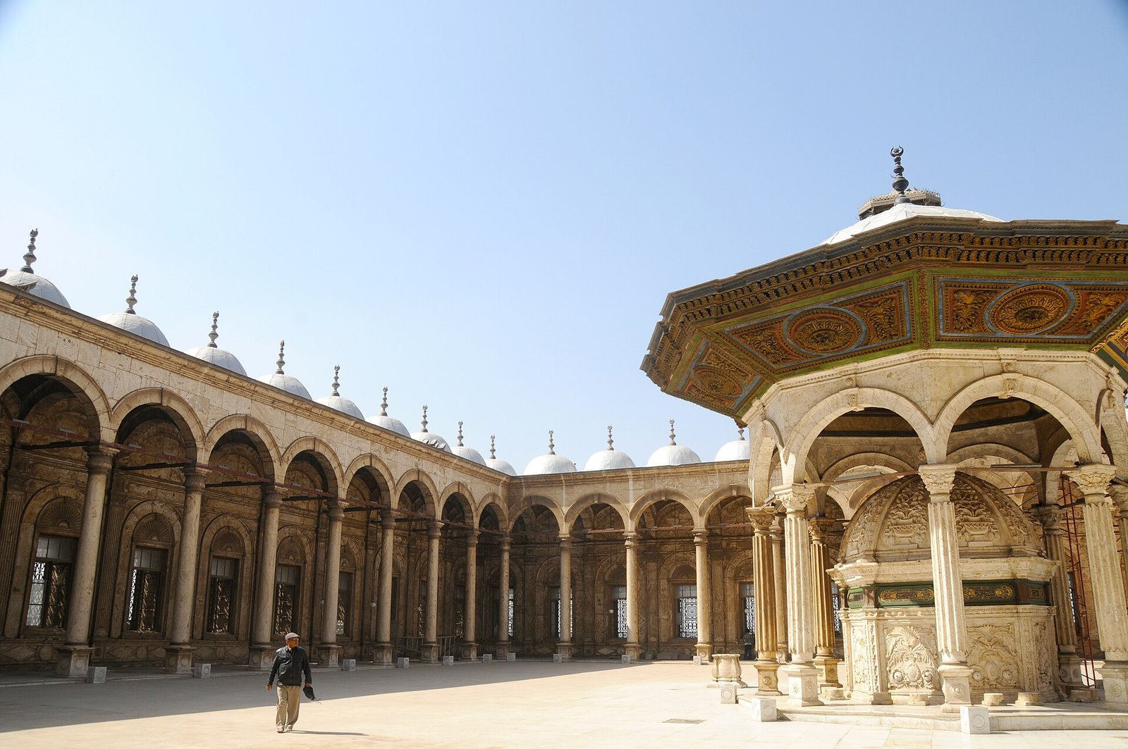 Patio de alabastro de la mezquita de Muhammad Ali en El Cairo, Egipto, con el pabellon dorado de la fuente y la arcada de cupulas blancas bajo cielo azul