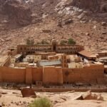Monasterio de Santa Catalina con muros dorados al pie de las montanas de granito rojizo del Monte Sinai, Egipto, bajo luz calida y cielo despejado