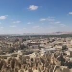 Vista panoramica del Oasis de Siwa en Egipto con la fortaleza de adobe de Shali, el palmeral verde y los lagos salados al fondo bajo cielo azul