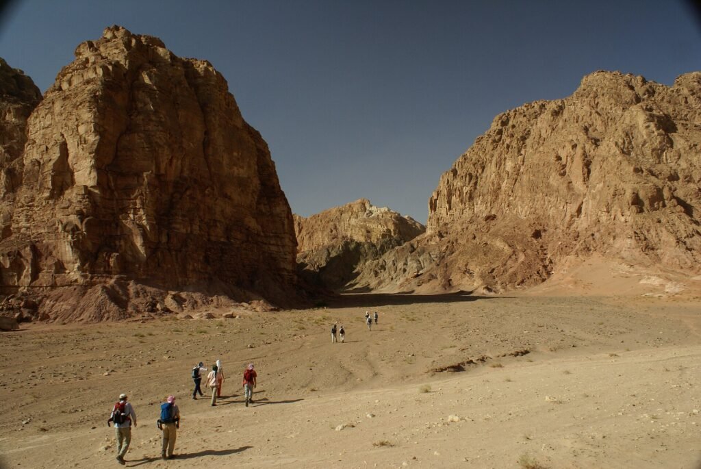 Espectacular valle desertico de la Peninsula del Sinai en Egipto con grandes macizos de arenisca rojiza enmarcando un wadi arenoso bajo un cielo azul intenso