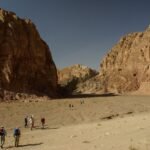 Espectacular valle desertico de la Peninsula del Sinai en Egipto con grandes macizos de arenisca rojiza enmarcando un wadi arenoso bajo un cielo azul intenso