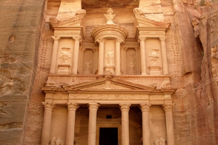 La fachada del Tesoro Al-Khazneh de Petra tallada en roca rosada en Jordania, con columnas y frontones iluminados por luz dorada calida