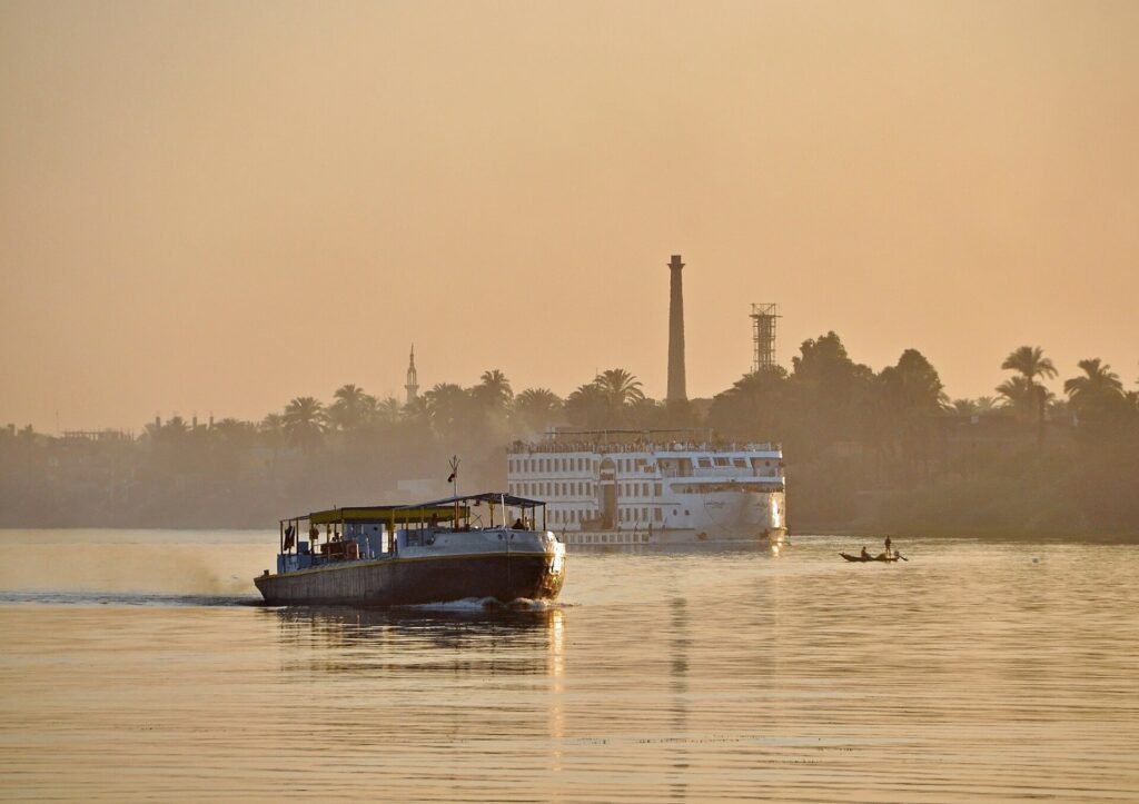 Crucero por el Nilo al atardecer dorado frente a la ribera de palmeras de Luxor en Egipto para planear el presupuesto de un viaje