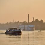 Crucero por el Nilo al atardecer dorado frente a la ribera de palmeras de Luxor en Egipto para planear el presupuesto de un viaje